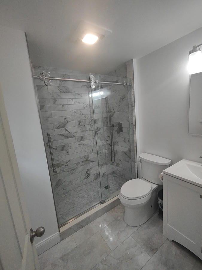 Teal tiled walk-in shower beside a dark vanity