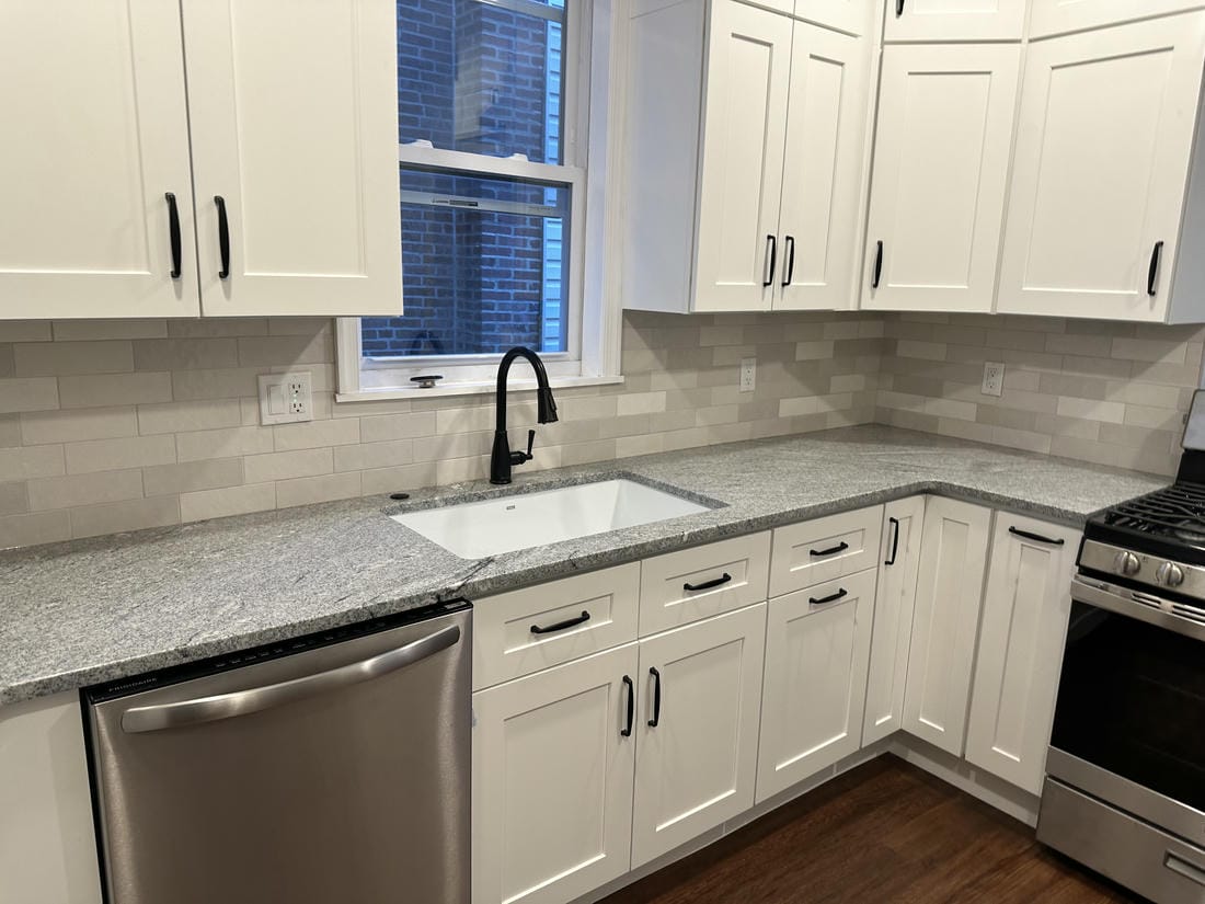 White kitchen remodel with an island and gray subway tile