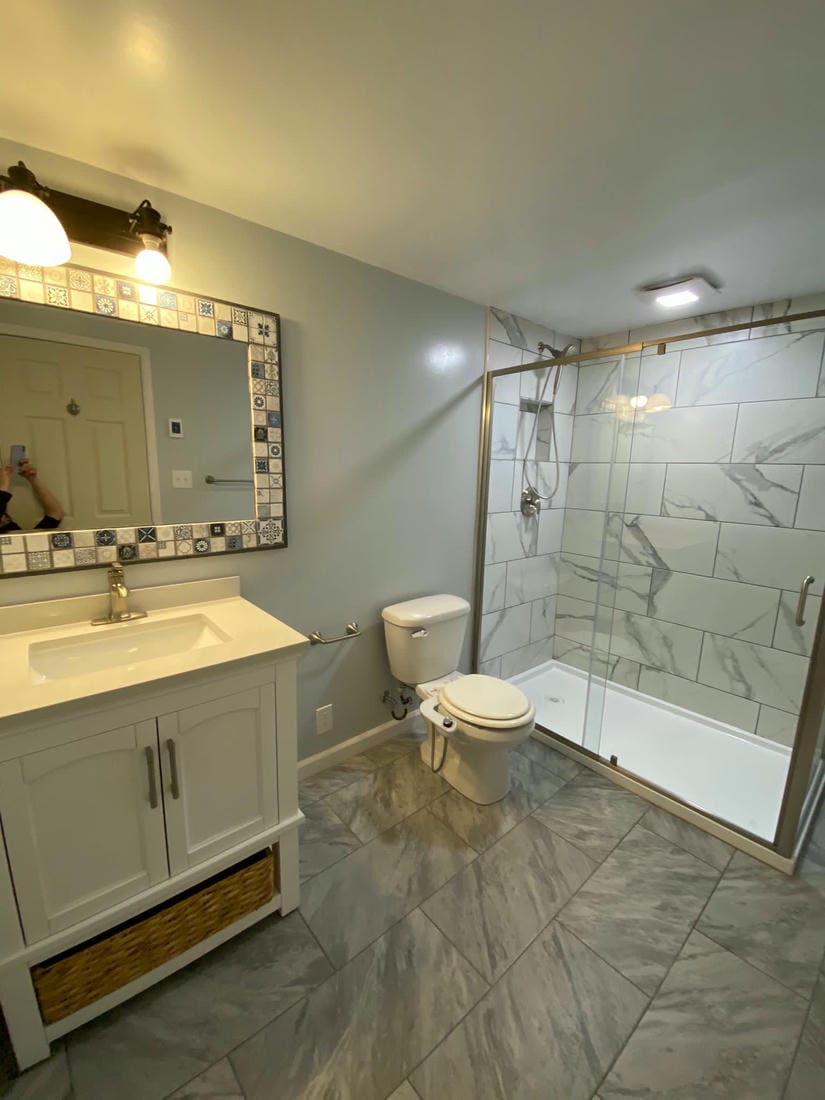 Teal tiled walk-in shower beside a dark vanity